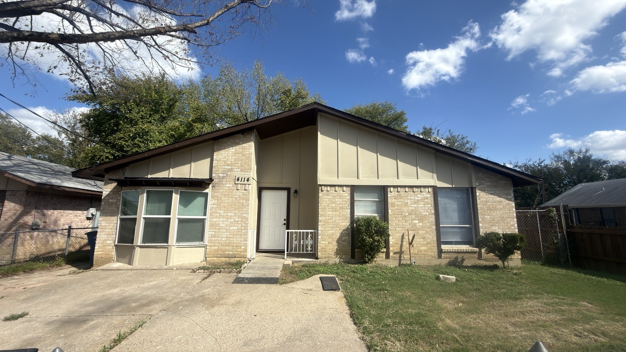 A house with a brown roof and a grey wall with a white door and windows.